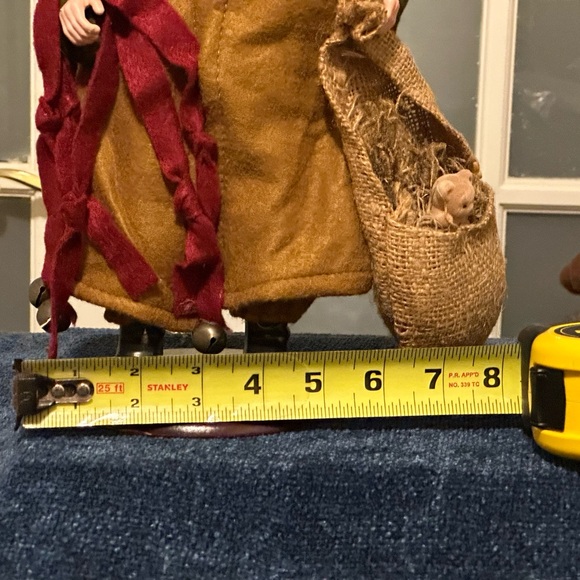 Shaggy haired and bearded Santa wears a brown cape and carries a burlap sack. - Picture 2 of 9